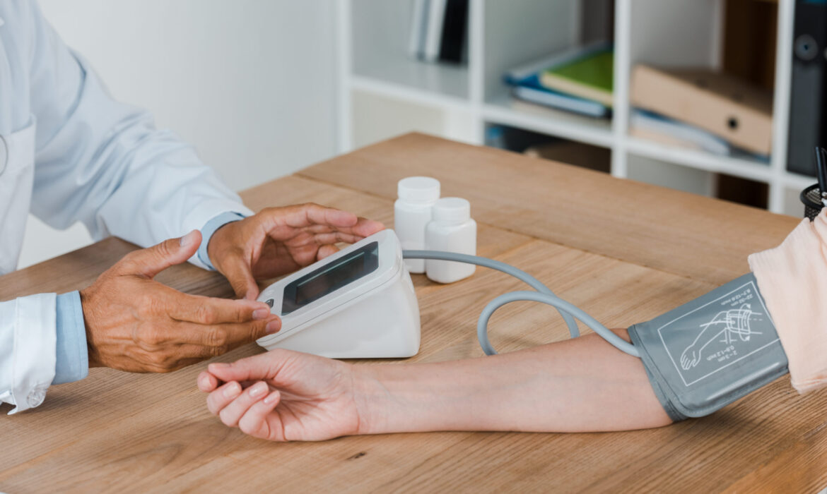 cropped view of doctor gesturing while measuring blood pressure of woman