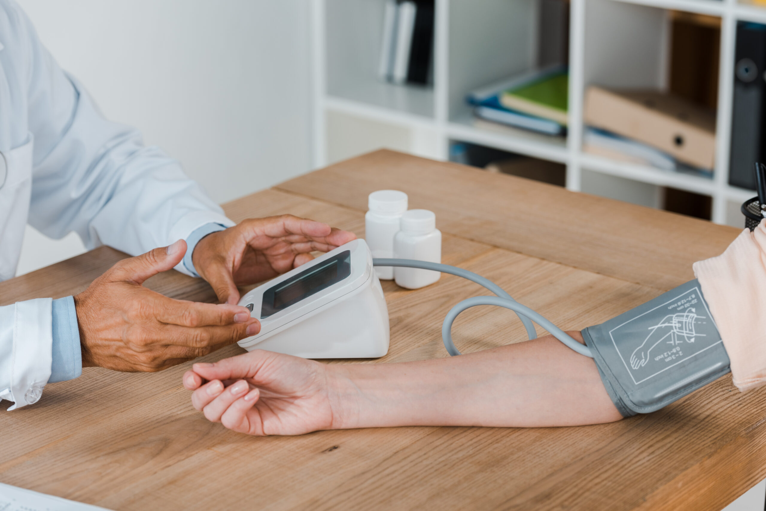 cropped view of doctor gesturing while measuring blood pressure of woman