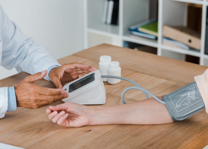 cropped view of doctor gesturing while measuring blood pressure of woman